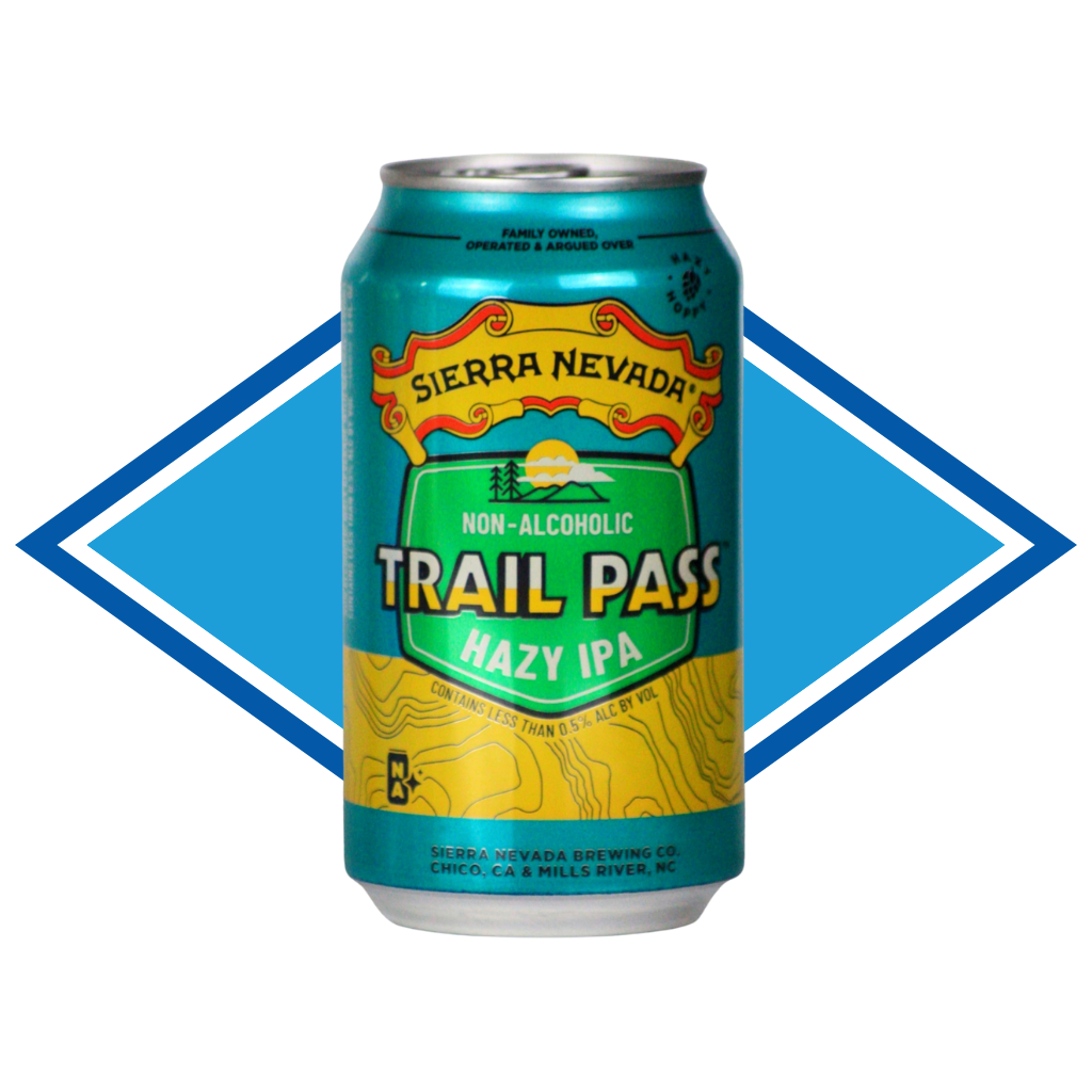 A 12 oz aluminum can of Sierra Nevada Trail Pass Hazy IPA non-alcoholic beer, featuring a teal, green, and yellow label with topographic line art, set against a blue and white diamond-shaped graphic background.