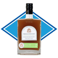 A bottle of Treguddick Non-Alcoholic Spirit of the Month Club, Volume 1, featuring amber liquid in a clear glass bottle with a black cap and a white label, set against a blue and white diamond graphic background.