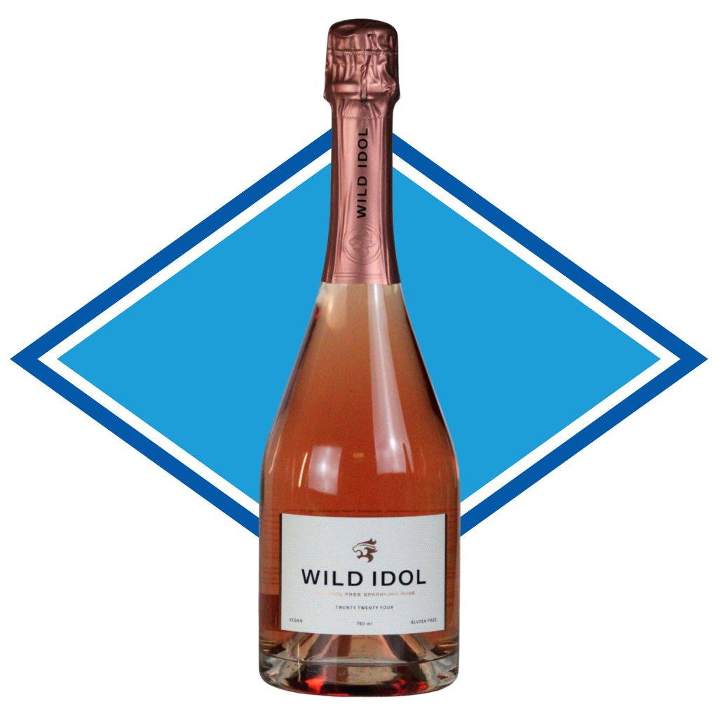 A bottle of Wild Idol Sparkling Rosé Pink wine, featuring a white label and a metallic rose gold foil neck, set against a blue and white diamond graphic on a white background.